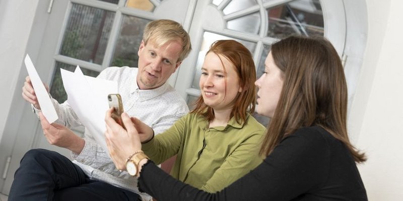 © Energieagentur Rheinland-Pfalz Drei Personen gemischten Alters betrachten gemeinsam, vertieft Dokumente und Handybilder